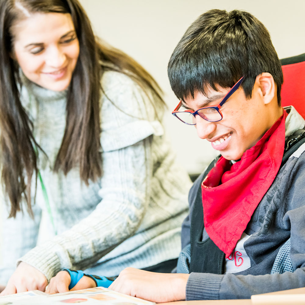Teacher supporting a pupil in a classroom setting